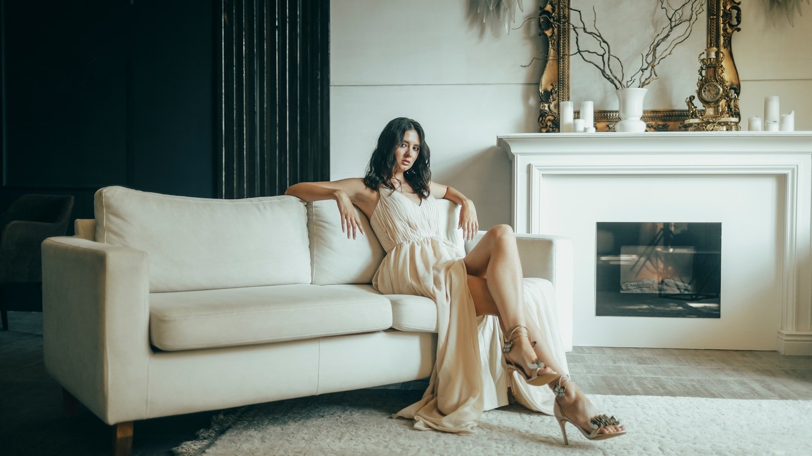 Woman in elegant dress relaxing on a white sofa.