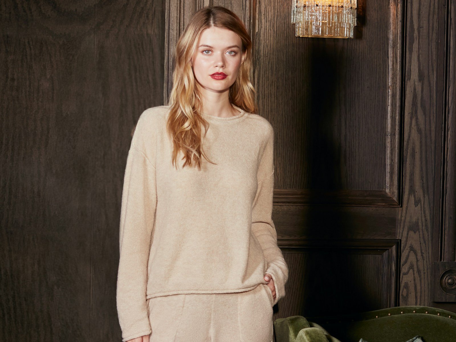 A blonde woman in a beige sweater and pants.